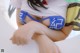 A woman in a white shirt and blue panties sitting on a chair.