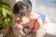 A woman in a red and blue bikini sitting on a window sill.