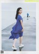 A woman in a blue dress is walking on a pier.