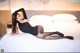 A woman in a black bodysuit laying on a bed.