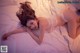 A woman laying on a bed in a white lingerie.