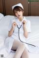 A woman dressed as a nurse sitting on a bed with a stethoscope.