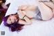 A woman with purple hair laying on a bed.