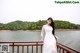 A woman in a white dress standing on a wooden bridge.